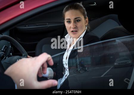 Burglar threatens young businesswoman sitting in car Stock Photo