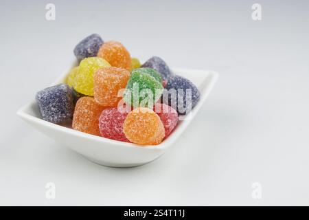 Appetizing and colorful jelly candies, coated with sugar, in a container on a white background Stock Photo