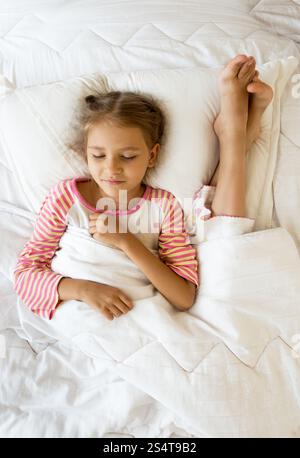 Indoor photo of girl lying next to sisters feet on pillow Stock Photo