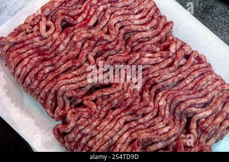 Fresh raw minced meat on paper, pork, beef, forcemeat close-up isolated on white background, top view. Stock Photo