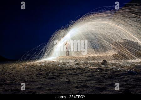 A steel wool on fire at night (night photography using a slow shutter speed) - galaxy background selective focused on the subject. Stock Photo