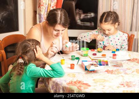 Portrait of mother with two daughters painting easter eggs Stock Photo