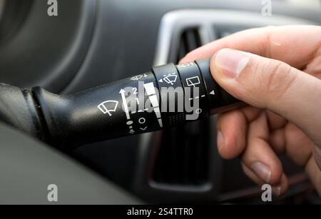Macro photo of driver adjusting windscreen wipers control toggle Stock Photo