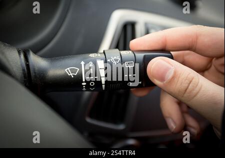 Closeup shot of male driver adjusting speed of screen wipers in car Stock Photo