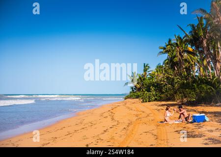Rio Grande, Puerto Rico - March 6, 2018: Couple enjoying a romantic picnic on secluded section of Luquillo Beach. Stock Photo