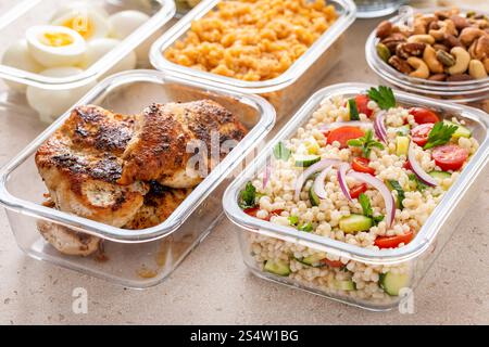 Vegetarian meal prep in containers with grilled chicken, eggs, lentils, roasted vegetables, nuts and pearl couscous salad Stock Photo