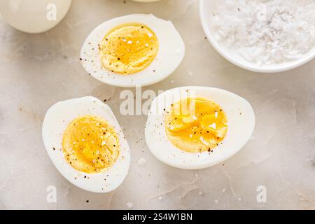 Soft boiled eggs cut in half with salt and black pepper Stock Photo