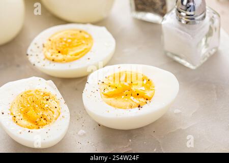 Soft boiled eggs cut in half with salt and black pepper Stock Photo