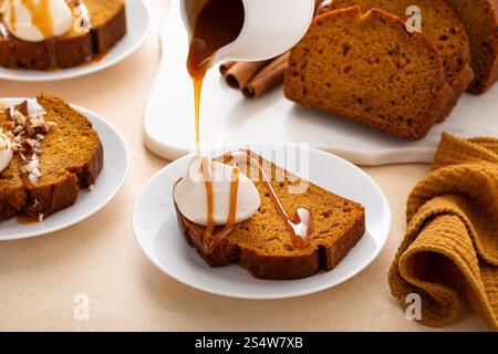 Pumpkin bread freshly baked topped with whipped cream and caramel syrup, Thanksgiving dessert idea Stock Photo