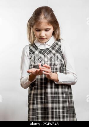 Portrait of cute little girl counting fingers against white background Stock Photo