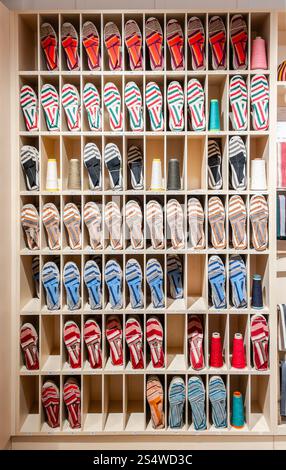 A display of colorful Espadrilles arranged neatly in wooden cubbyholes at a store. Stock Photo