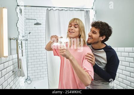 A cheerful moment unfolds as two men enjoy their morning routine, brushing teeth together. Stock Photo