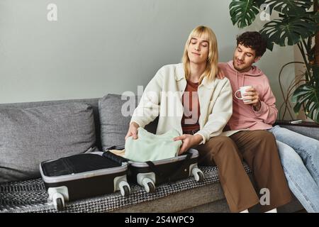 Two men share a tender moment while packing their bags for a trip, surrounded by warmth. Stock Photo