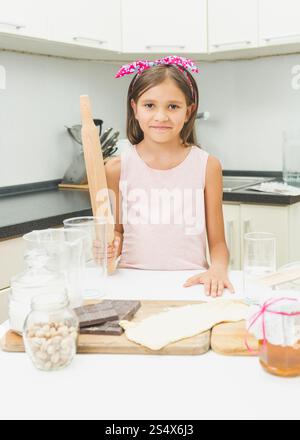 Toned portrait of cute smiling girl with rolling pin making dough Stock Photo