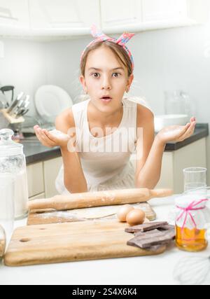 Portrait of funny girl making dough on kitchen Stock Photo