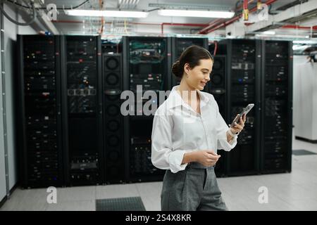 A dedicated woman in a white shirt monitors systems in a high-tech server room while working. Stock Photo