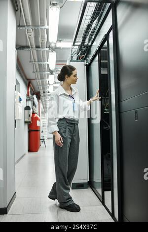 A woman in a white shirt inspects server hardware while ensuring digital security in a tech setting. Stock Photo