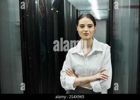 A woman in a white shirt oversees server operations in a sleek data center while ensuring security. Stock Photo