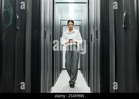 A woman in a white shirt navigates the server room, ensuring systems run smoothly. Stock Photo