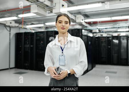 A skilled woman in a white shirt confidently oversees server operations in a tech hub. Stock Photo