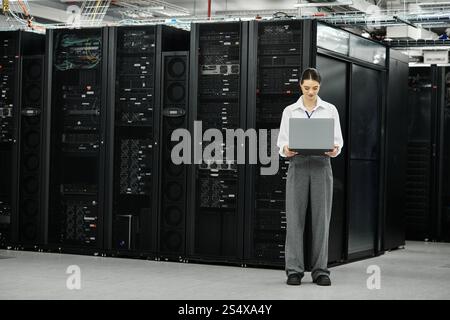 A skilled woman in a white shirt engages with server hardware in a high-tech environment. Stock Photo