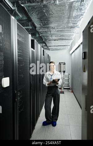 A skilled IT specialist expertly manages systems in a modern server room, showcasing her expertise. Stock Photo