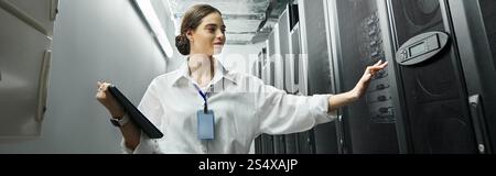 Specialist in a white shirt monitors server systems in a high-tech, professional environment, banner Stock Photo