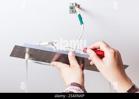 Electrician fixes wiring in ceiling lamp indoor Stock Photo