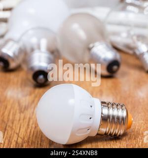 new LED lamp and old incandescent light bulbs and used compact Fluorescent lamps on table Stock Photo