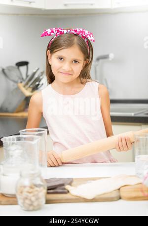 Portrait of cute smiling girl with rolling pin making dough Stock Photo