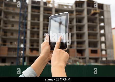 Young woman posing on building site and using digital tablet Stock Photo