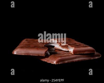 Broken chocolate bar with cream filling on black background, close-up, low key photo Stock Photo