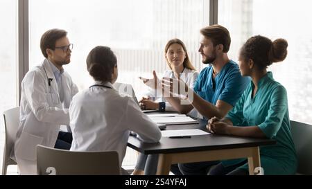 Young doctor make speech during briefing with diverse clinic workmates Stock Photo