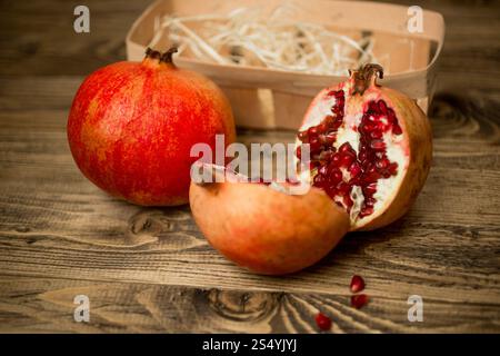 Closeup of two halves of pomegranate on old wooden board Stock Photo