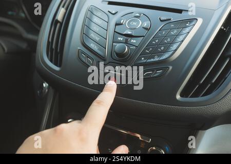 Closeup of driver pressing emergency button on car dashboard Stock Photo