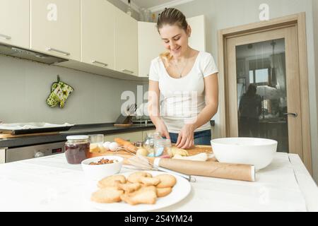 Beautiful young woman making dough on kitchen at home Stock Photo