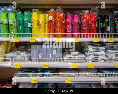 Italy - December 08, 2024: Plastic cups in packs of various colours and plastic cutlery on shelves for sale in Italian supermarket Stock Photo
