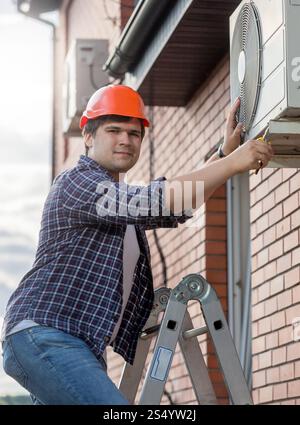 Young technician repairing outside air conditioning unit Stock Photo