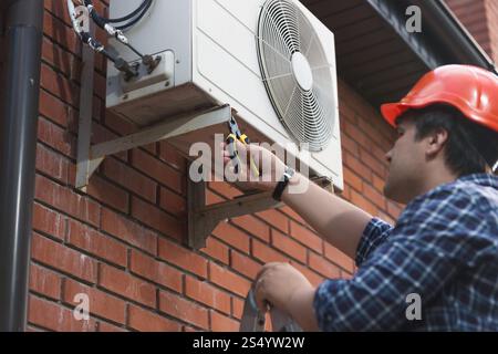 Technician in hardhat connecting outdoor air conditioning unit Stock Photo