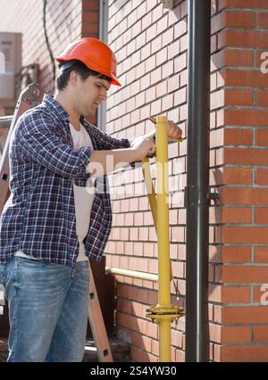 Plumber in hardhat repairing pipes at house Stock Photo