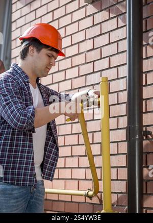 Young plumber in hardhat repairing pipes Stock Photo