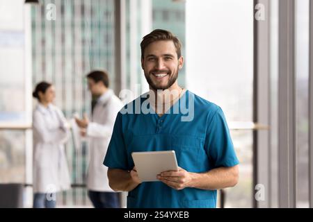 Young handsome man medical worker in scrubs holding digital tablet Stock Photo