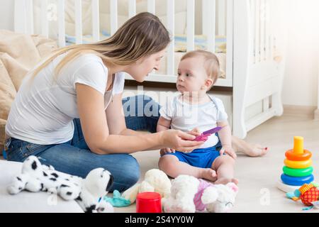 Beautiful young mother playing with her baby on floor Stock Photo