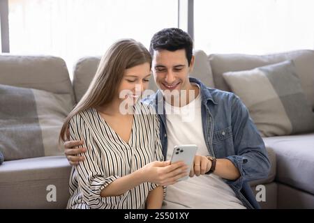 Positive Latin husband and wife using application on mobile phone Stock Photo