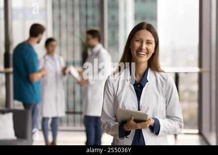 Beautiful female medical worker in white coat holding digital tablet Stock Photo