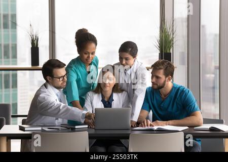 Five professional medical workers working together using laptop Stock Photo