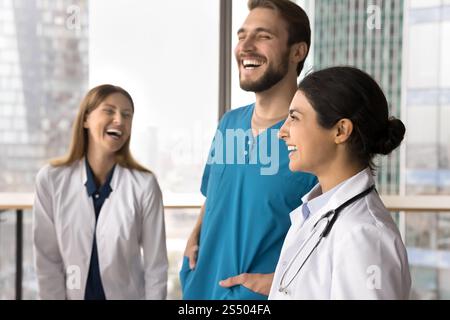 Three multiethnic doctors in uniforms, laughing, sharing lighthearted moments Stock Photo
