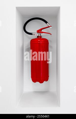 Red fire extinguisher hanging in niche on white wall for first aid Stock Photo