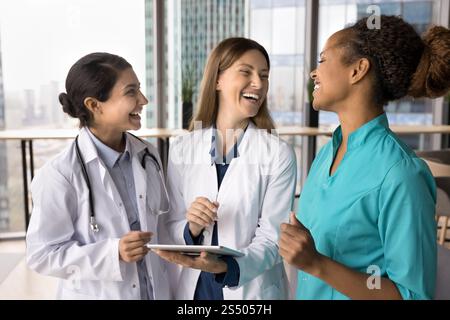 Three general practitioners colleagues laughing, lead conversation during break Stock Photo