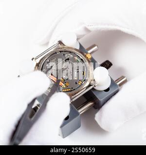 watchmaker workshop - replacing battery in quartz wristwatch close up by tweezers on white background Stock Photo